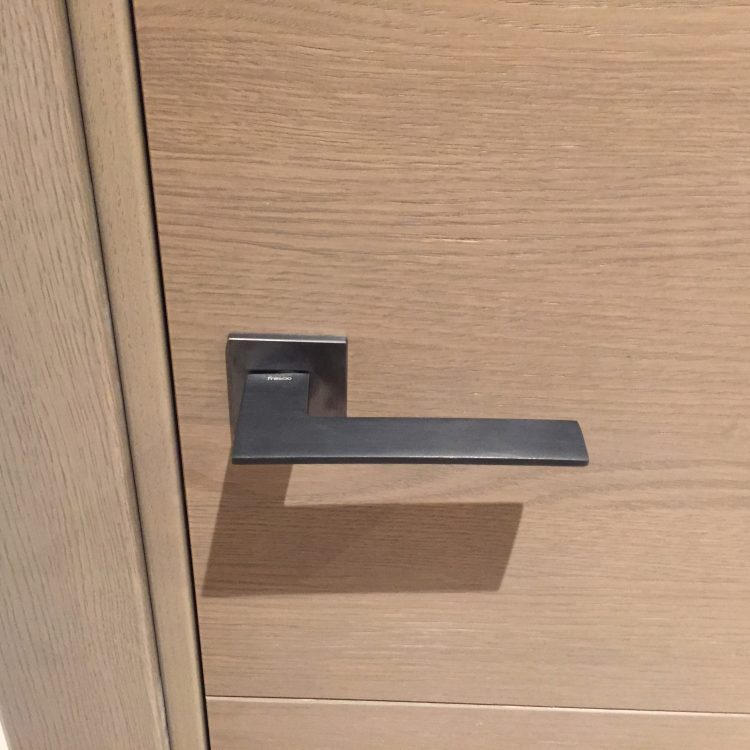 Poignée de porte gris anthracite sur porte en chêne teinté gris crête